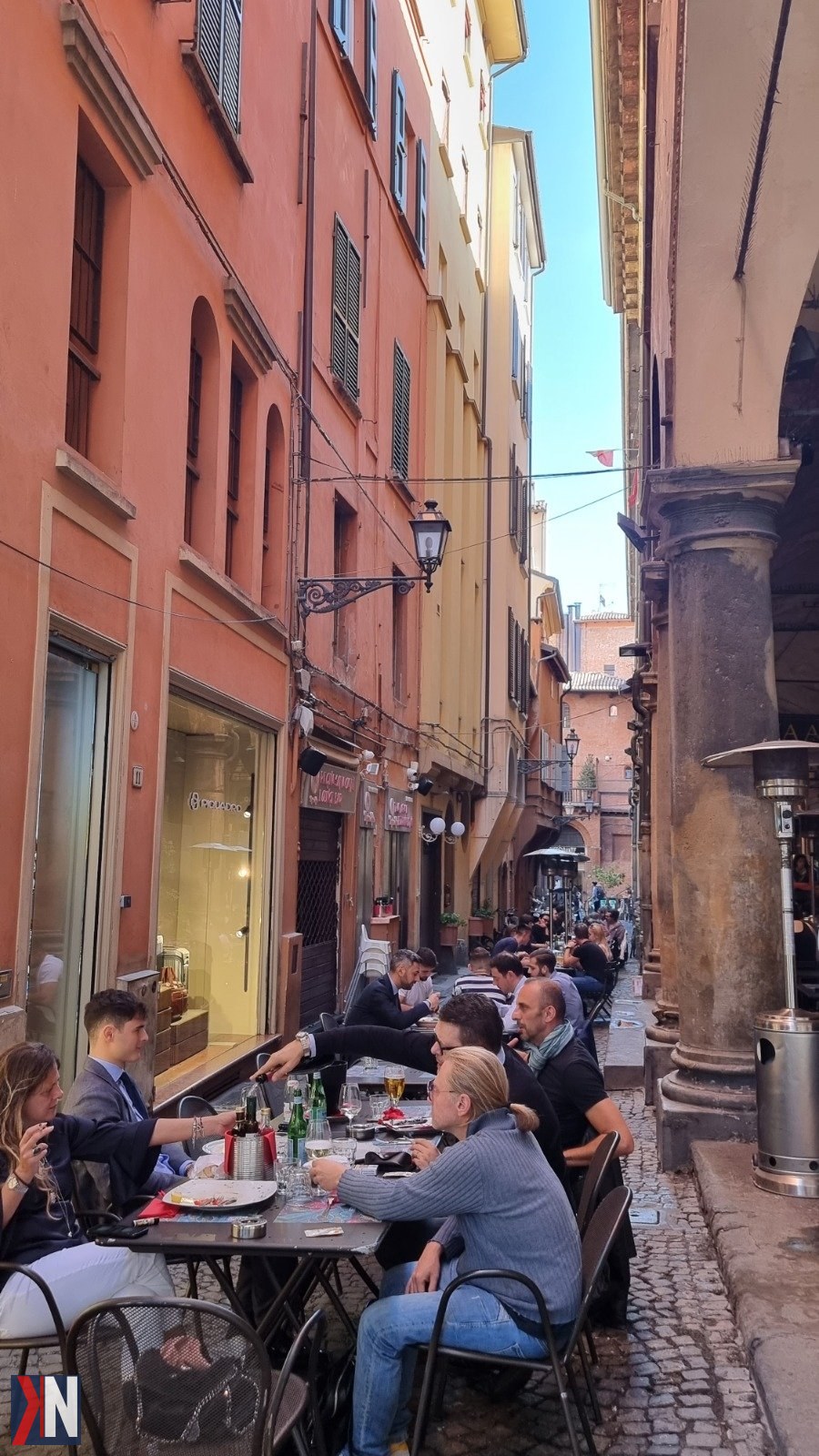 "Zdjęcie przedstawia malowniczą ulicę Bolonii, pełną kolorowych budynków i urokliwych kawiarenek, idealną na spacer i relaks. To doskonałe miejsce na naładowanie baterii podczas podróży do Bolonii, gdzie każda chwila sprzyja odkrywaniu uroków tego włoskiego miasta."