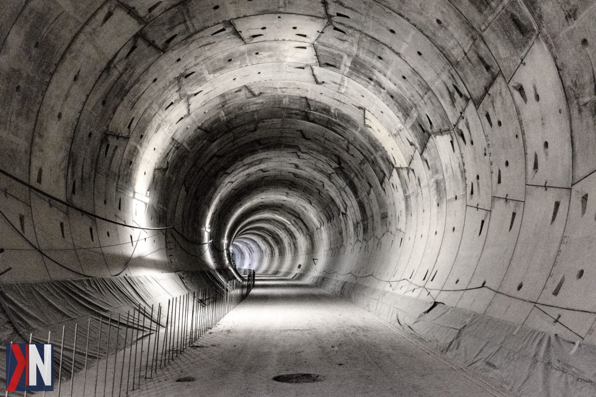"Obraz przedstawiający tunel średnicowy w Łodzi, ilustrujący najnowsze decyzje administracyjne wydane przez Łódzki Urząd Wojewódzki, które umożliwiają wznowienie prac budowlanych. Na zdjęciu widać sprzęt budowlany, kamienice oraz tarczę TBM, symbolizującą postęp projektu kolejowego."