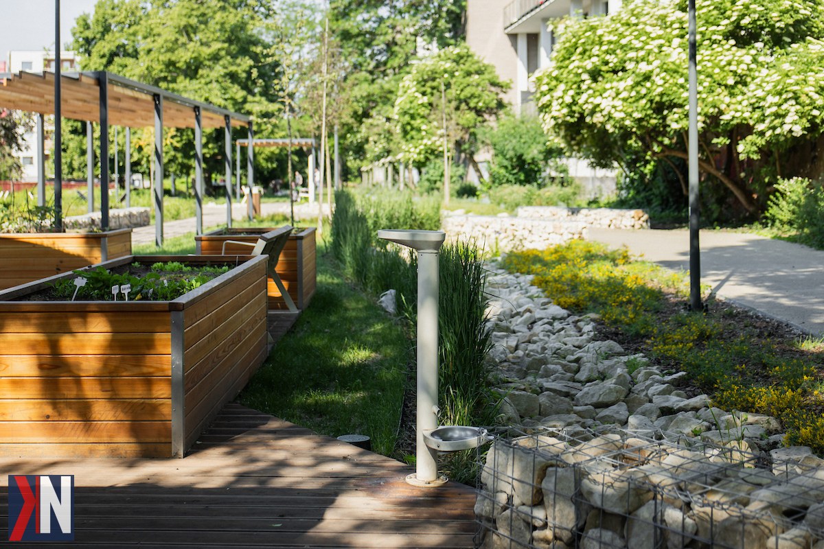 "Zdjęcie przedstawiające nowoczesny park w Łodzi, otoczony zielenią, z kwitnącymi drzewami i alejkami spacerowymi. W artykule omawiamy transformację Łodzi z szarego miasta przemysłowego w przestrzeń pełną małych parków miejskich, które tworzą przyjazne miejsce do odpoczynku i rekreacji."