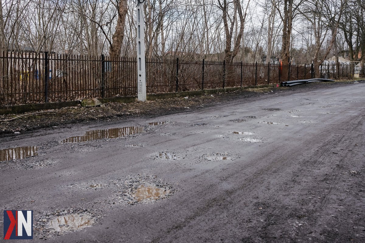 "Zdjęcie przedstawia ekipę drogowców pracujących na ul. Dąbrowa w Łodzi, gdzie trwają prace związane z inwestycjami drogowymi i rowerowymi. W tle widać oznakowanie budowy oraz pojazdy służbowe, co symbolizuje powrót budowniczych na ulice miasta wraz z nadejściem wiosny."