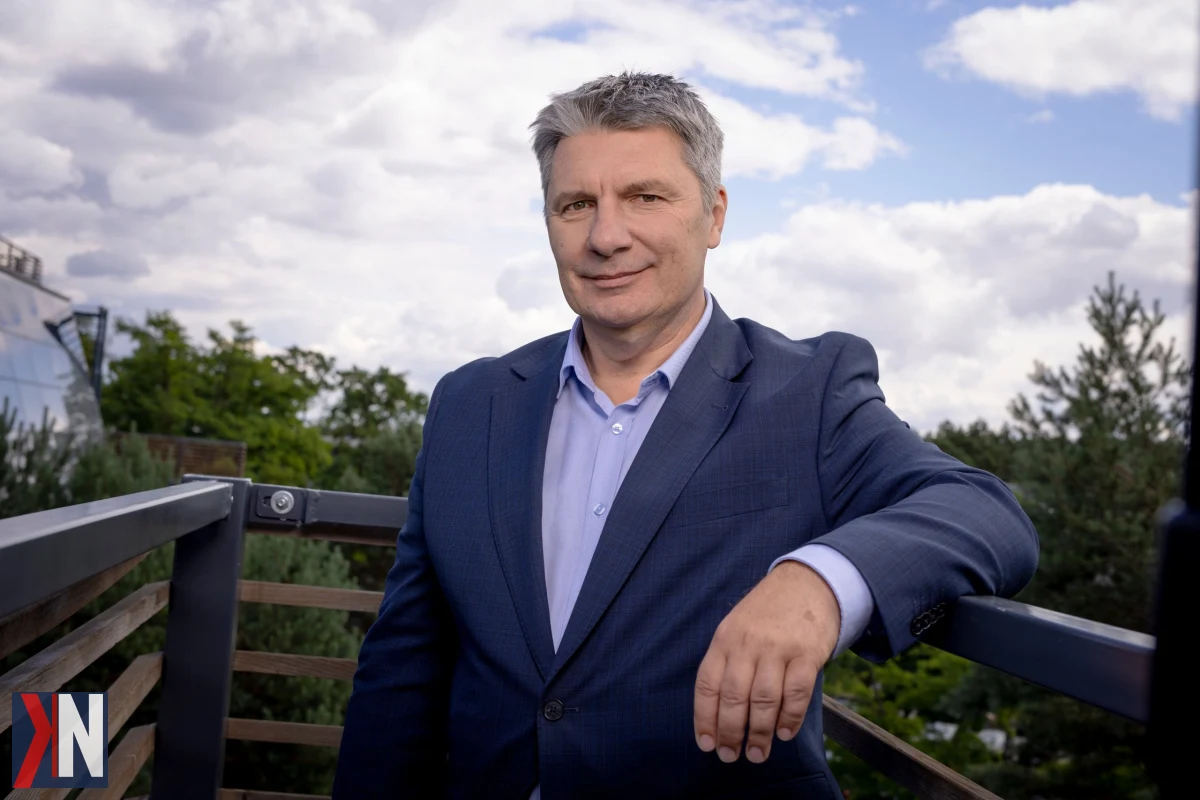 Zdjęcie przedstawia Piotra Kopka, eksperta z WFOŚiGW w Łodzi, omawiającego nowe programy dotyczące czystego powietrza, retencji wody oraz wsparcia w wysokości 300 mln zł. W tle widok na Łódź, symbolizujący wyzwania takie jak smog, azbest i susze, które dotykają mieszkańców regionu.