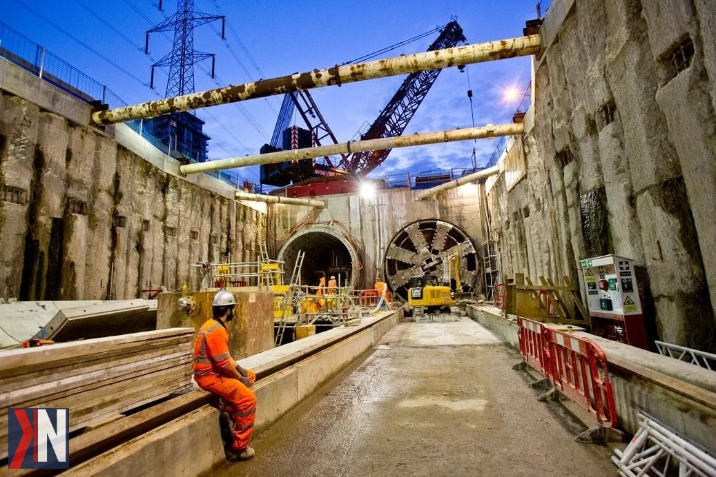 Zdjęcie przedstawia tarcze TBM (Tunnel Boring Machines) w Łodzi, które służą do budowy tuneli kolejowych. W artykule omówiono, jak duże miasta, jak Londyn i Paryż, prowadzą prace tunelarskie pod swoimi metropoliami. W Łodzi dwie tarcze TBM są kluczowe w zakończeniu projektu tunelu średnicowego, który napotkał trudności w realizacji.