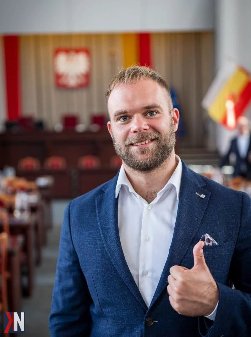 Kosma Nykiel, radny Rady Miejskiej w Łodzi, analizuje wyzwania komunikacyjne miasta. Jako doświadczony urbanista i społecznik, podkreśla, że sam tunel średnicowy nie wystarczy do rozwiązania problemów transportowych Łodzi. Zdjęcie przedstawia Nykiela w trakcie publicznej dyskusji na temat polityki transportowej, z mapą Łodzi w tle.