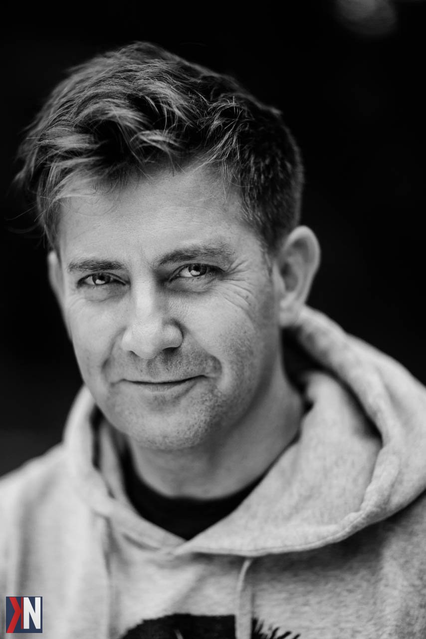 "Zdjęcie z kawiarni Costa w Manufakturze w Łodzi, gdzie fotografka kobiecych dusz spotyka się z modelką. W tle widać pofabryczne wnętrze z wysokimi sufitami i surową cegłą, idealne do uchwycenia intymnych chwil. W atmosferze artystycznego spokoju, dwie kobiety dzielą się swoimi historiami przy filiżance kawy."