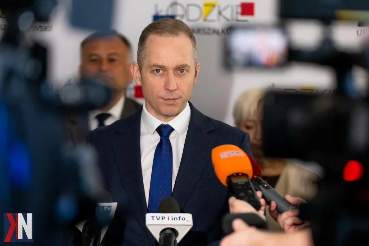 "Zdjęcie Cezarego Tomczyka, Ministra, który ogłasza plany ulokowania wojsk rakietowych w Łowiczu, z perspektywą rozwoju jednostek dronowych w przyszłości. W tle widać aktywność militarną oraz lokalną infrastrukturę, symbolizującą powrót służb wojskowych do regionu."