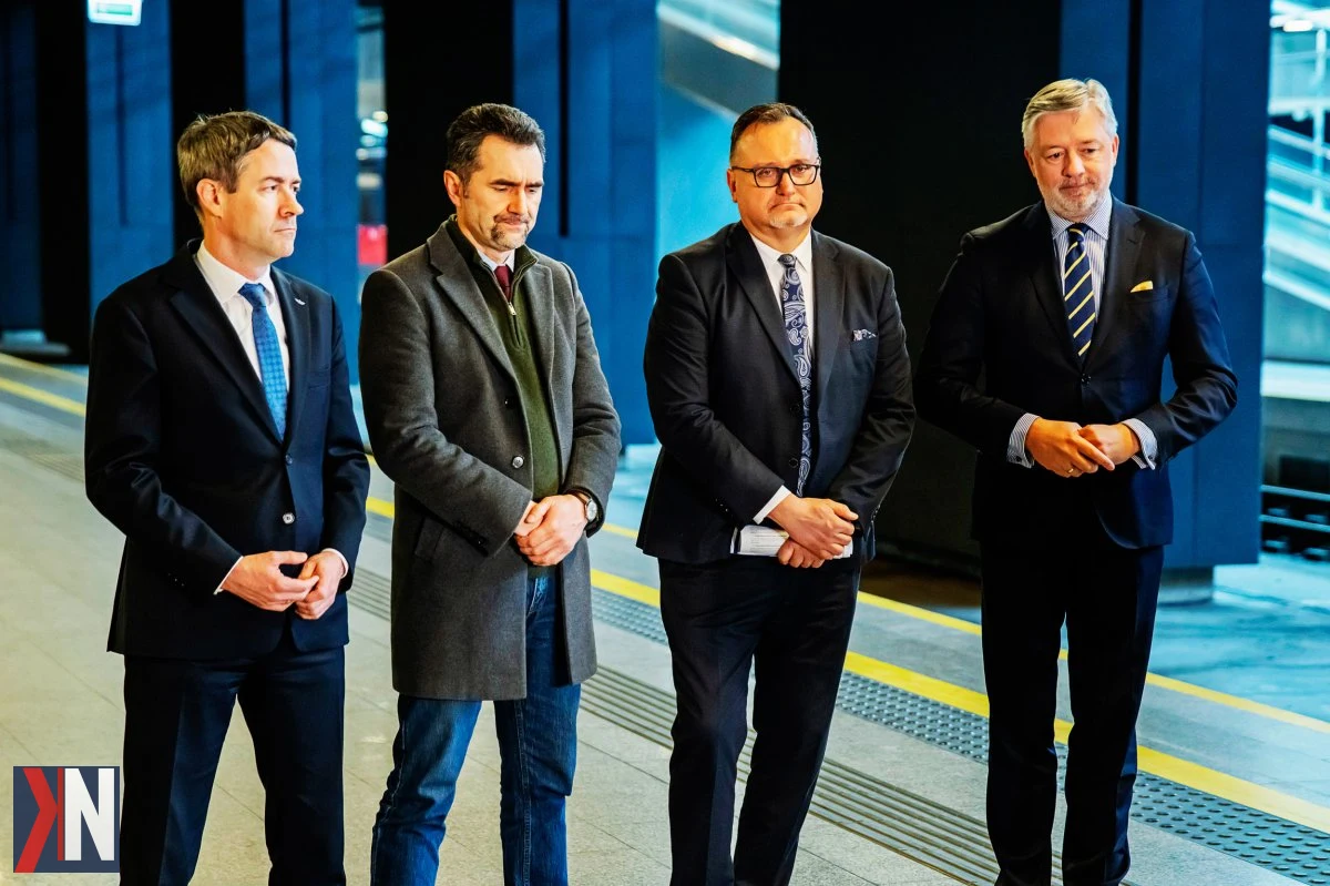 "Europosłowie podczas wizyty w Łodzi, gdzie omawiają wpływ tunelu średnicowego i dworca Łódź Fabryczna na rozwój KDP. Inwestycje mają na celu umożliwienie szybkiej podróży do Berlina i Wiednia w zaledwie 4 godziny. W tle widoczny nowoczesny dworzec oraz infrastruktura, które stanowią istotny argument w rozmowach z Brukselą."