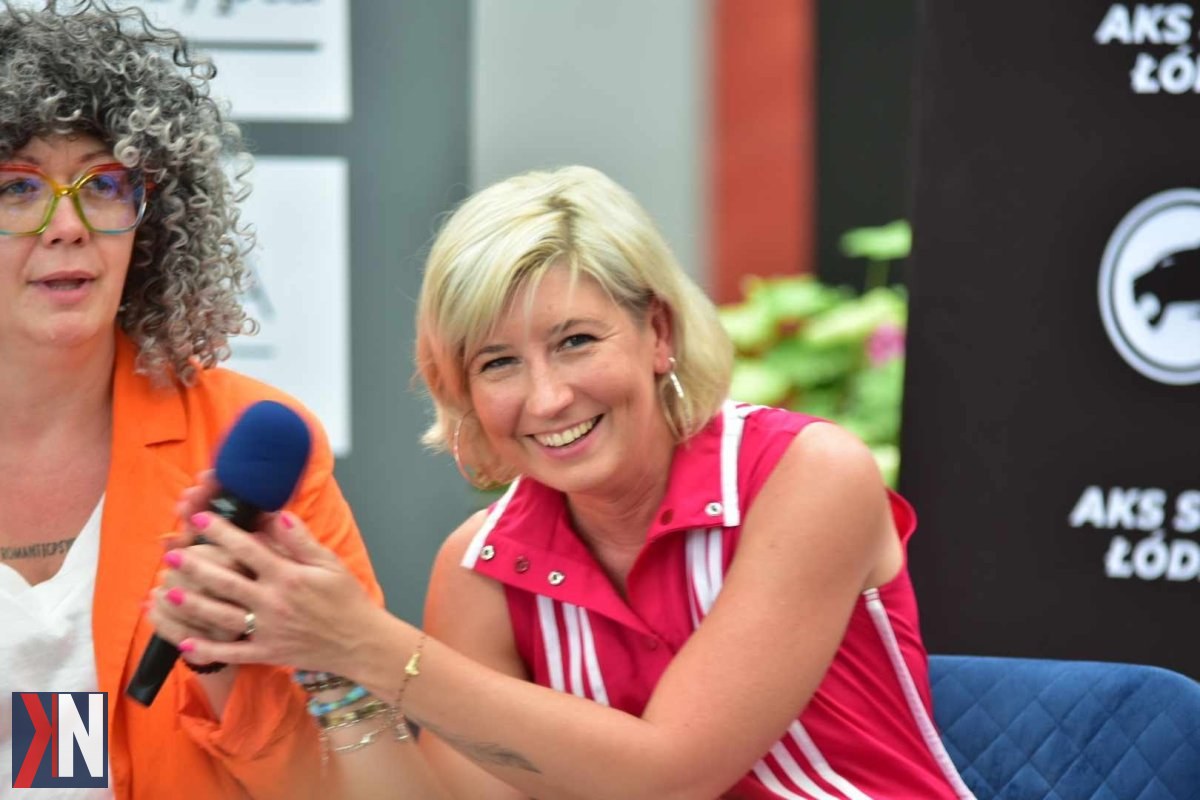 "Zdjęcie przedstawia Agnieszkę Płoszaj, łódzką autorkę kryminałów, uśmiechającą się podczas rozmowy o wyzwaniach związanych z byciem pisarzem i dynamicznym rynkiem wydawniczym. W tle widać książki na półkach, co podkreśla jej pasję do literatury. Tematyka rozmowy dotyczy pisania bestsellerów i indywidualnego tempa pracy twórczej."