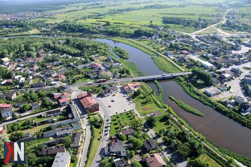 Zdjęcie ilustrujące artykuł o kontrowersjach związanych z budową dróg ekspresowych S12 i S74 w województwie łódzkim, z tłem przedstawiającym fragment drogi oraz pracowników GDDKiA analizujących dokumenty dotyczące decyzji środowiskowych.