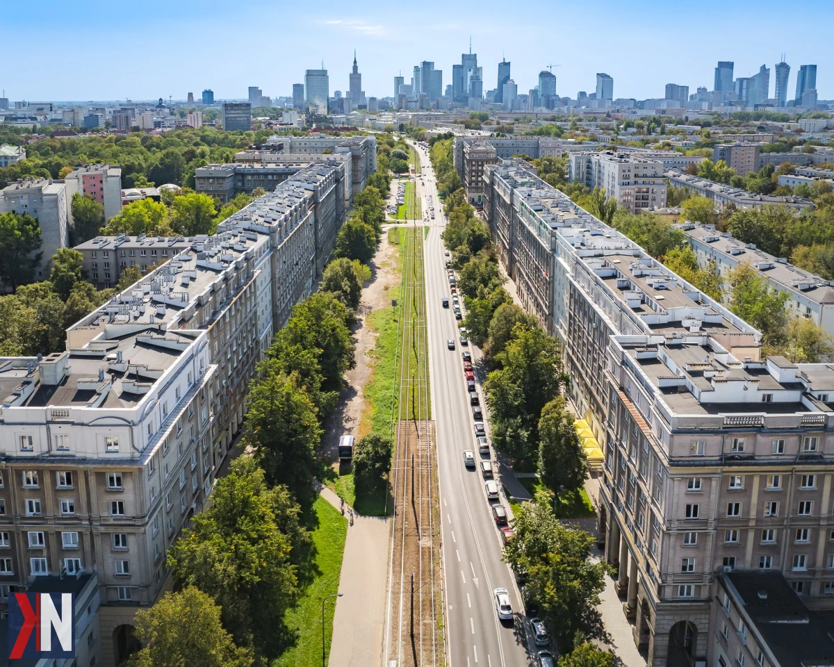 Zielony park kieszonkowy przy ulicy Andersa w Warszawie z drewnianymi tarasami, zaprojektowany przez Zarząd Zieleni m.st. Warszawy - nowa przestrzeń do wypoczynku i rekreacji na terenie byłego żwirowiska.