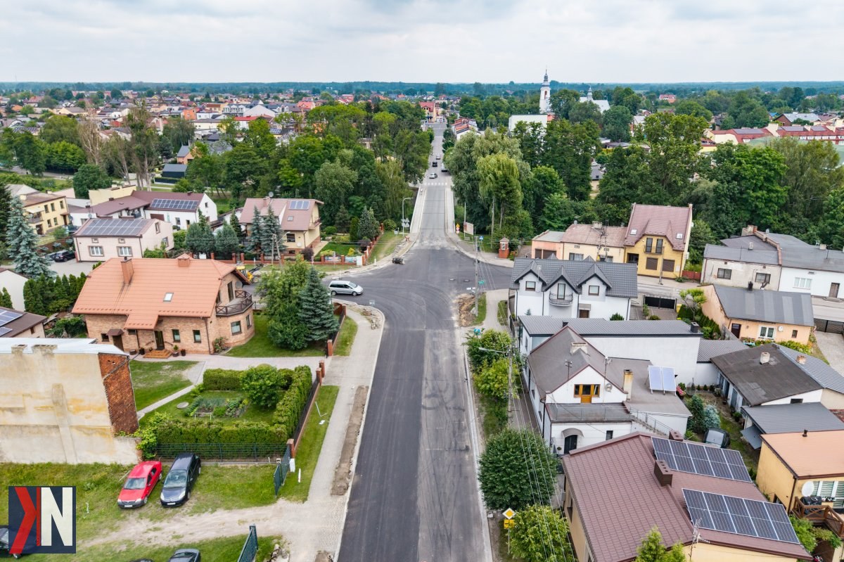 "Zdjęcie przedstawia prace remontowe na drodze wojewódzkiej nr 485 pomiędzy Drużbicami a Czarnym Lasem w województwie łódzkim, ukazujące maszyny budowlane oraz robotników zaangażowanych w modernizację infrastruktury drogowej."